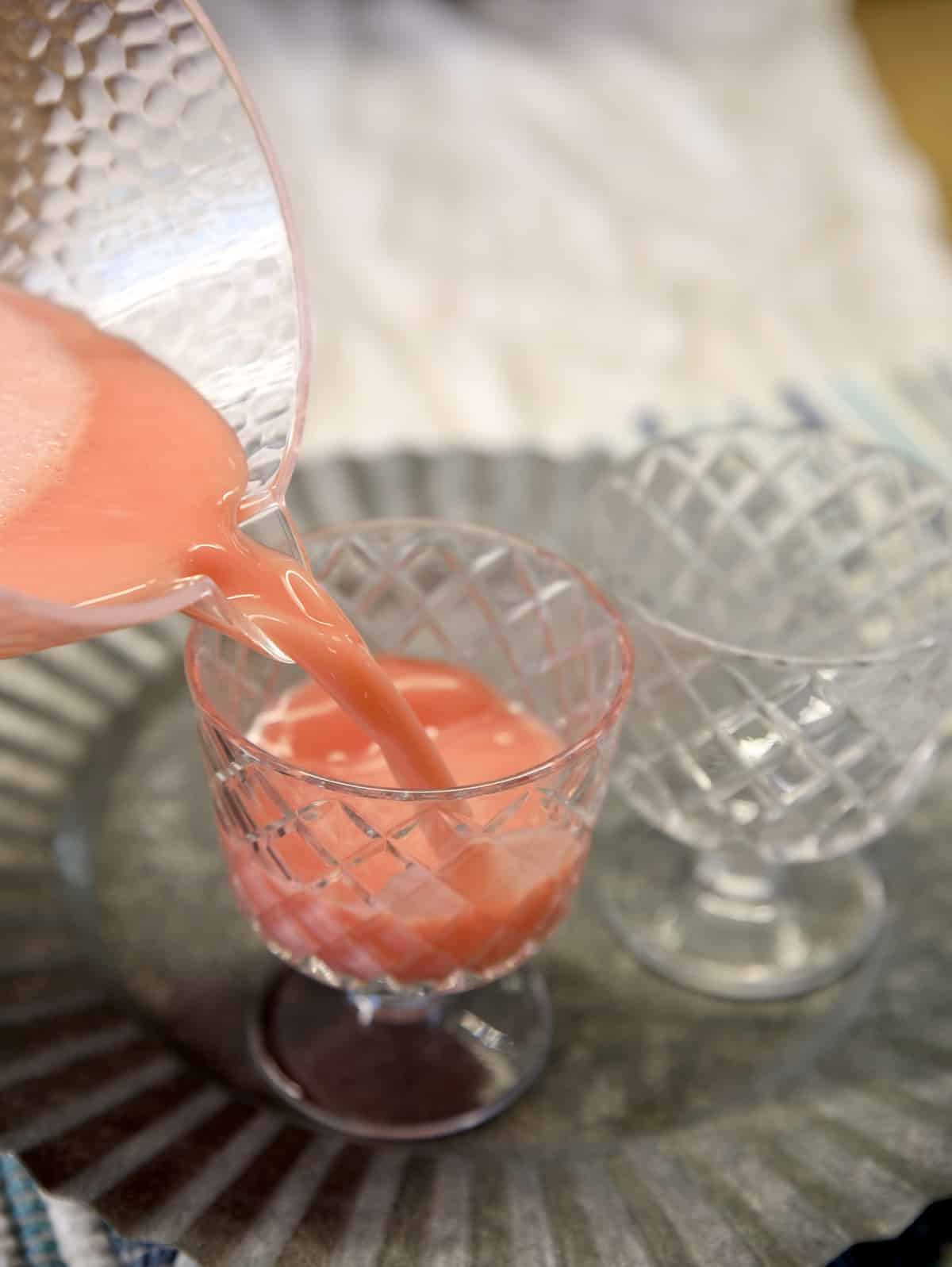 Pouring pink sherbet punch into party glasses.