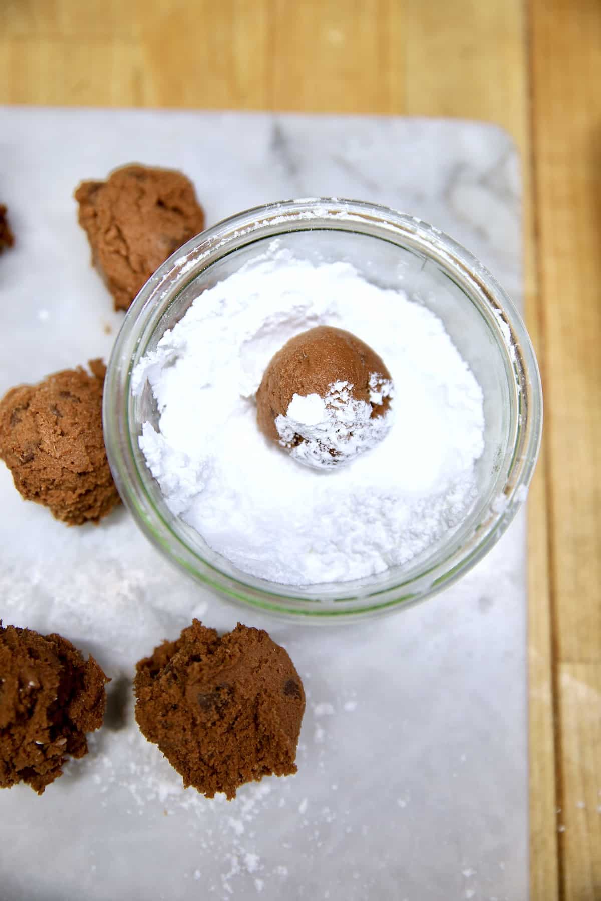 Rolling chocolate cookie dough in powdered sugar.