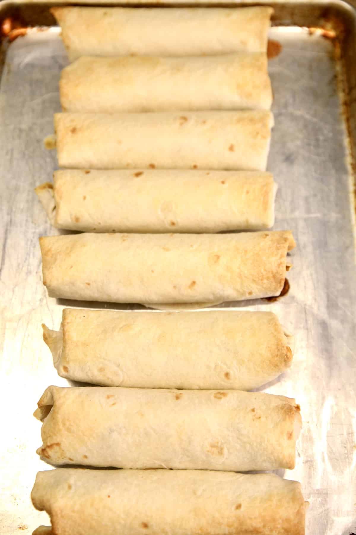Crispy baked burritos on a sheet pan.