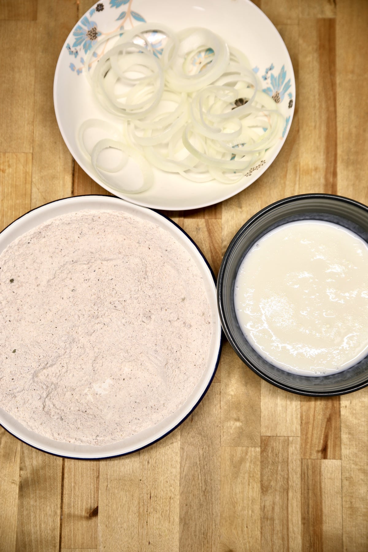 Sliced onions, seasoned flour, buttermilk in 3 bowls.
