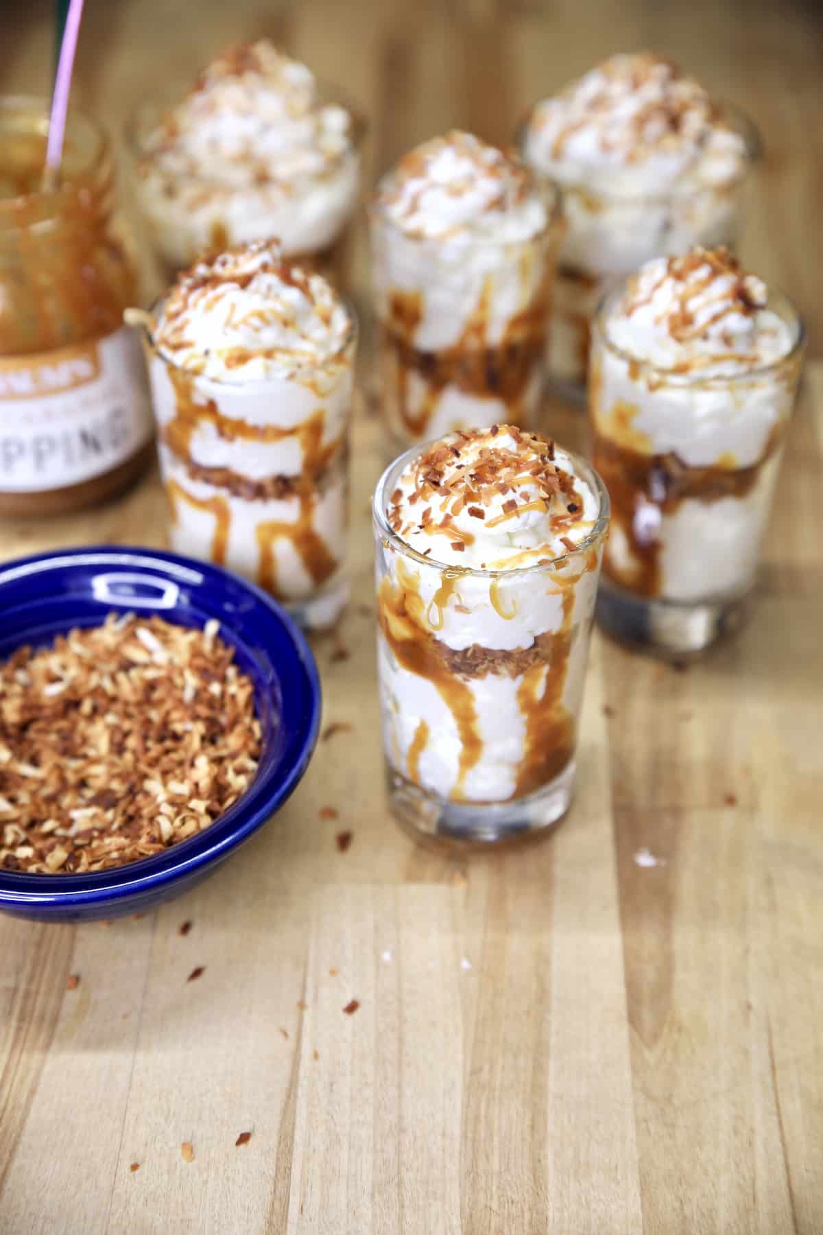 No Bake Coconut cheesecake in glasses drizzled with caramel sauce.