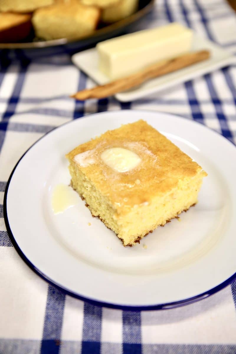 Slice of cornbread on a small plate, melting butter on top.