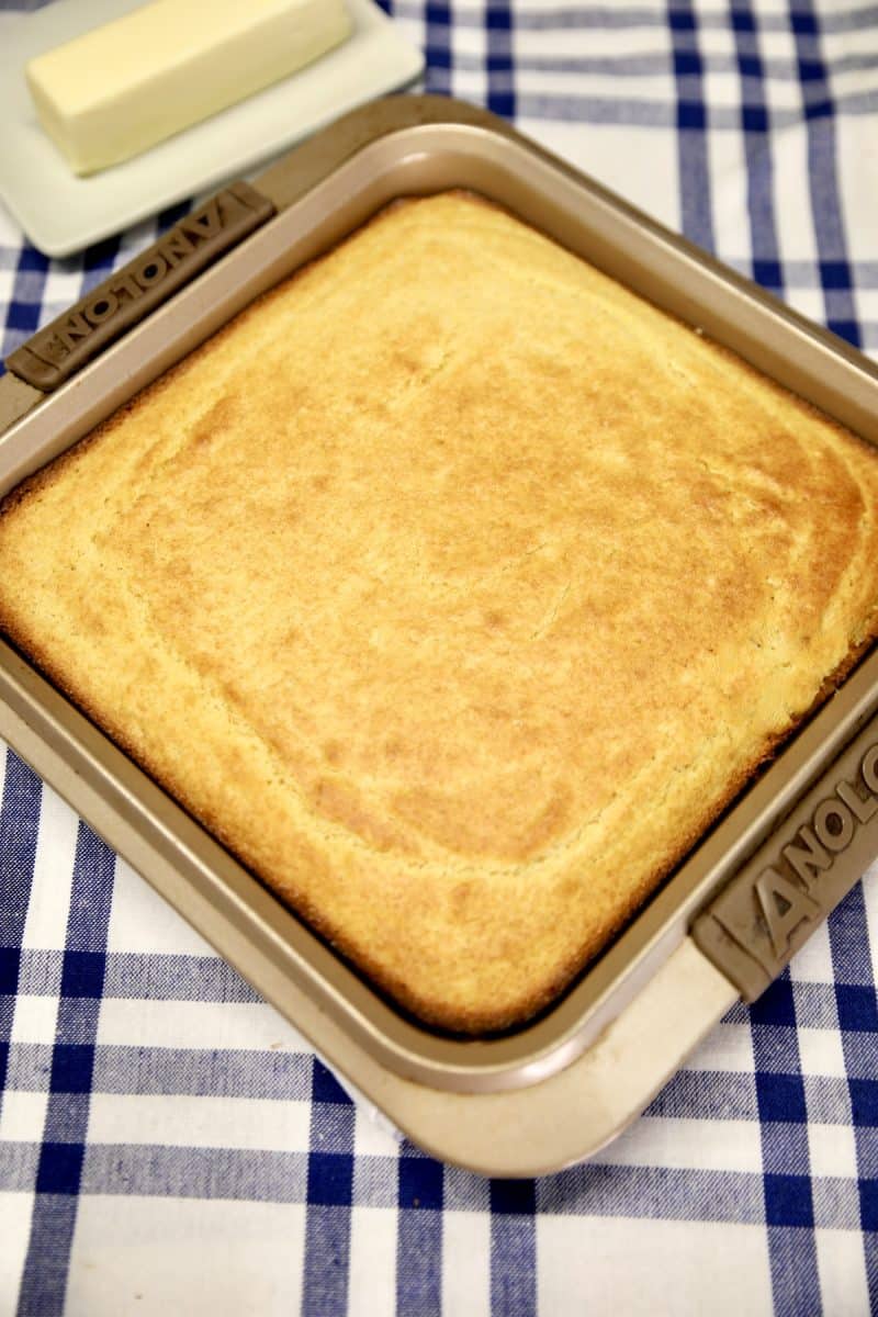 Pan of baked cornbread on a blue & white checked cloth.