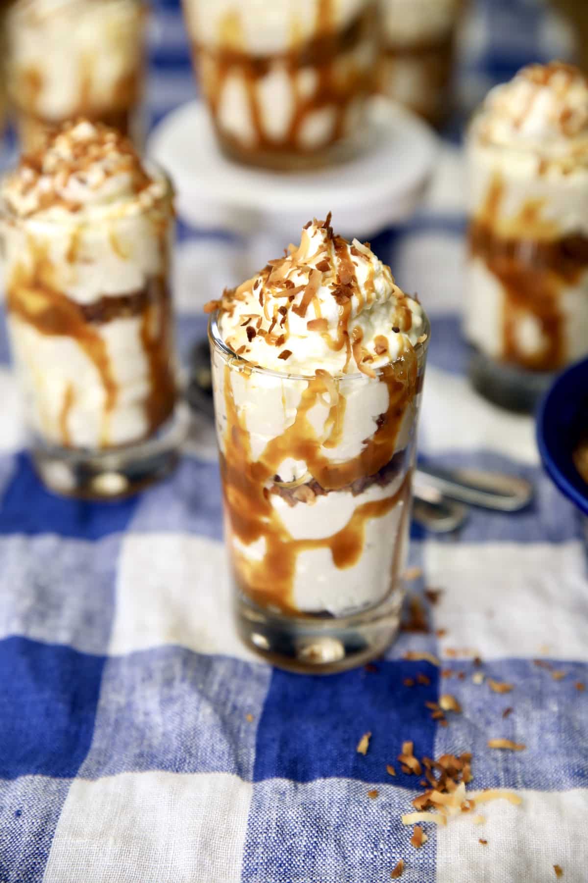 Dessert glasses with coconut cheesecake and caramel drizzle.