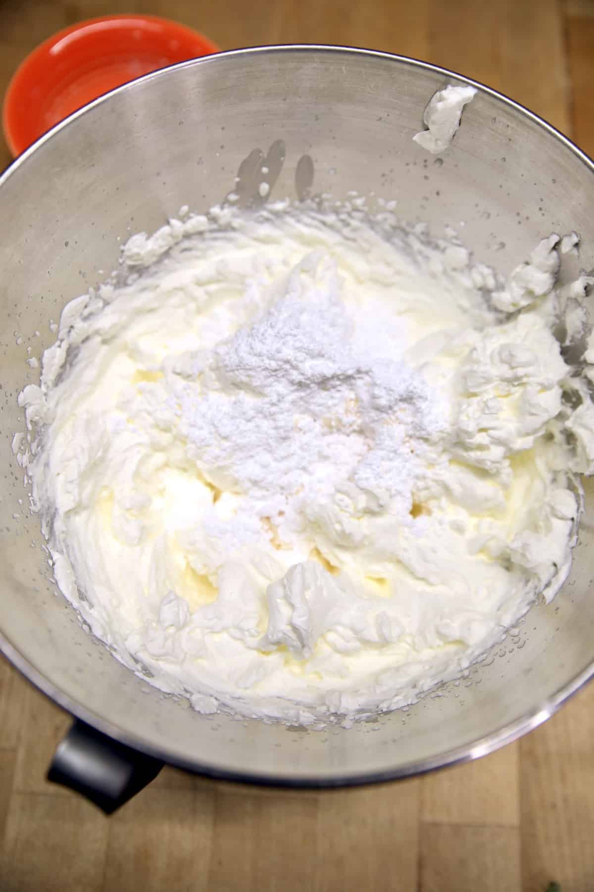 Whipped cream with powdered sugar in a mixer bowl.