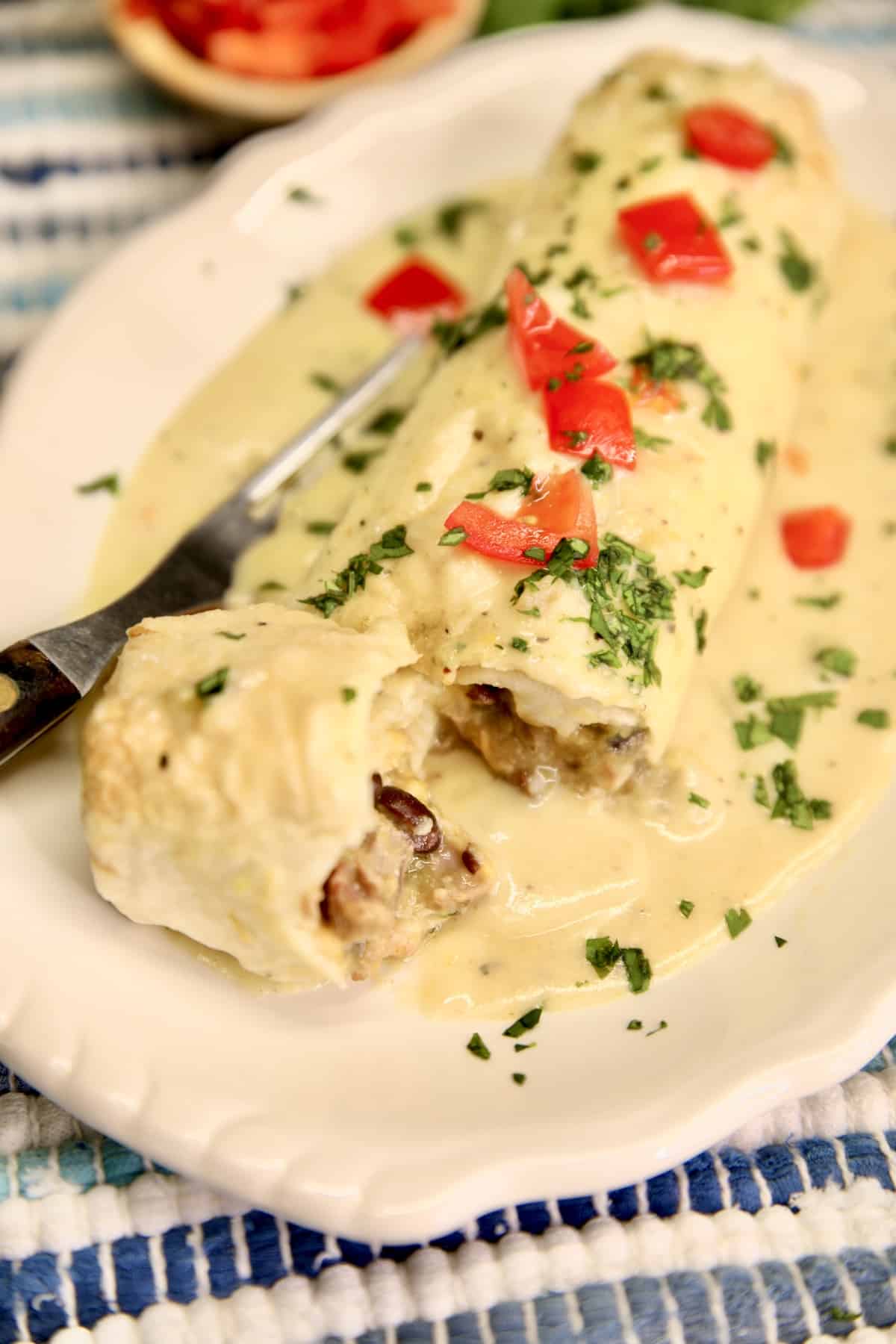 Chicken burrito with green chile sauce, cut to show filling.