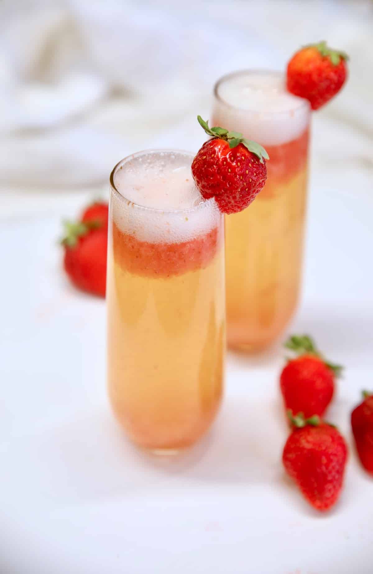 2 strawberry mimosa cocktails with strawberry garnish.
