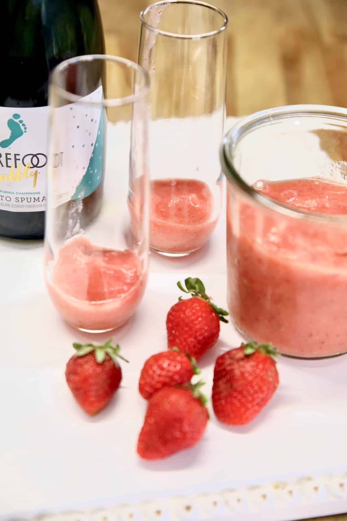 Champagne glasses with strawberry puree and fresh strawberries.