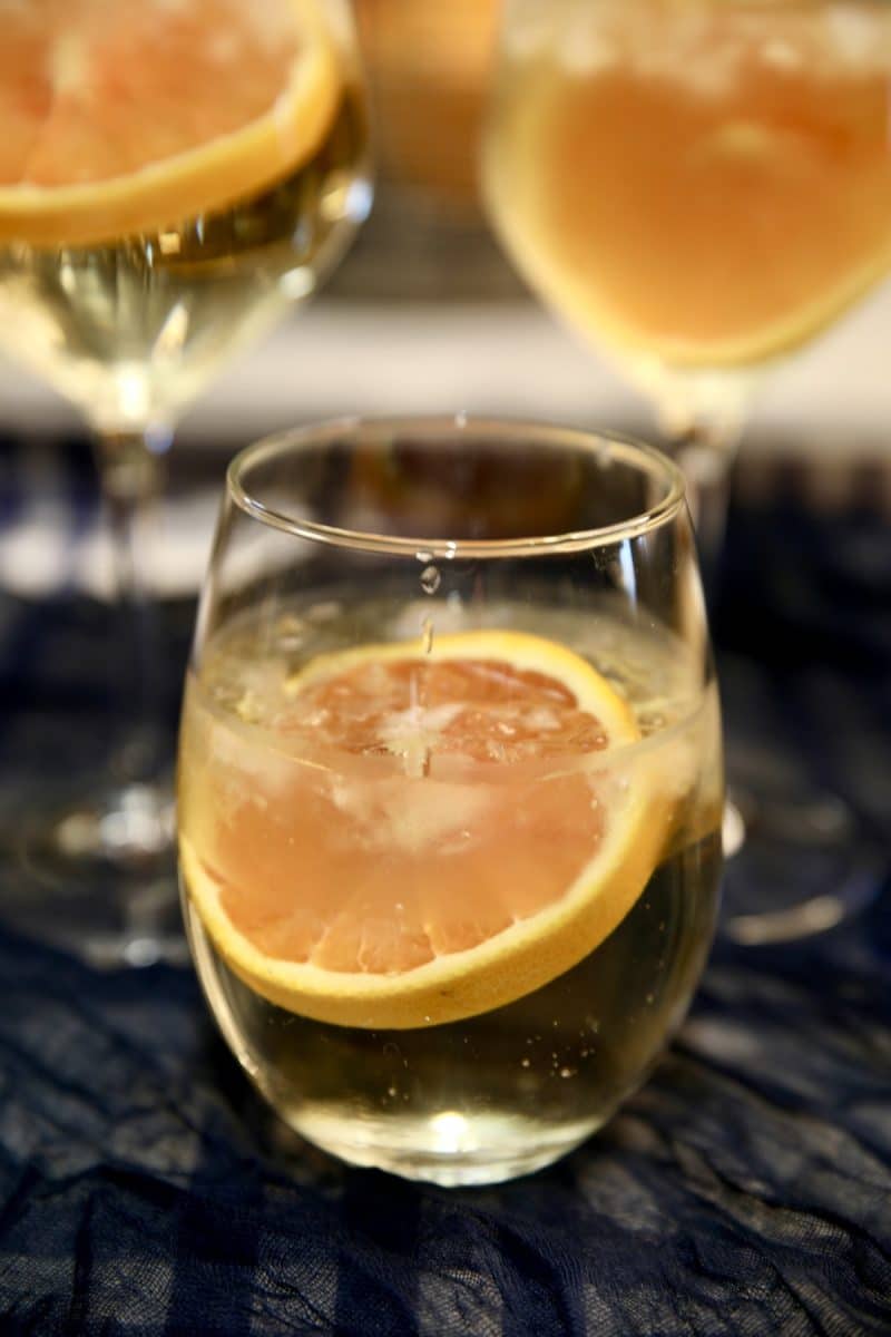 3 glasses of white wine spritzers- orange garnishes.