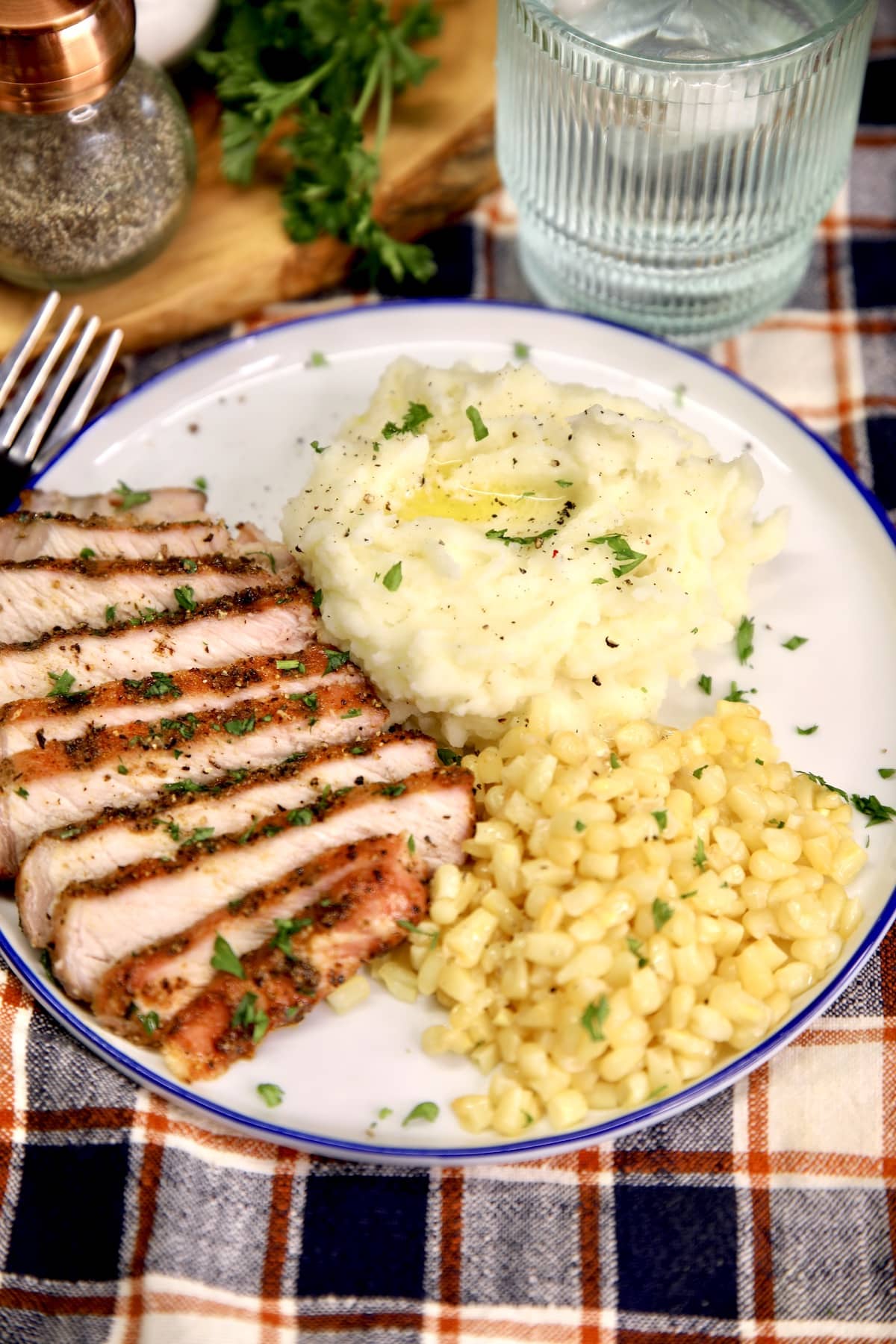 Plate of sliced pork chops with mashed potatoes and corn.