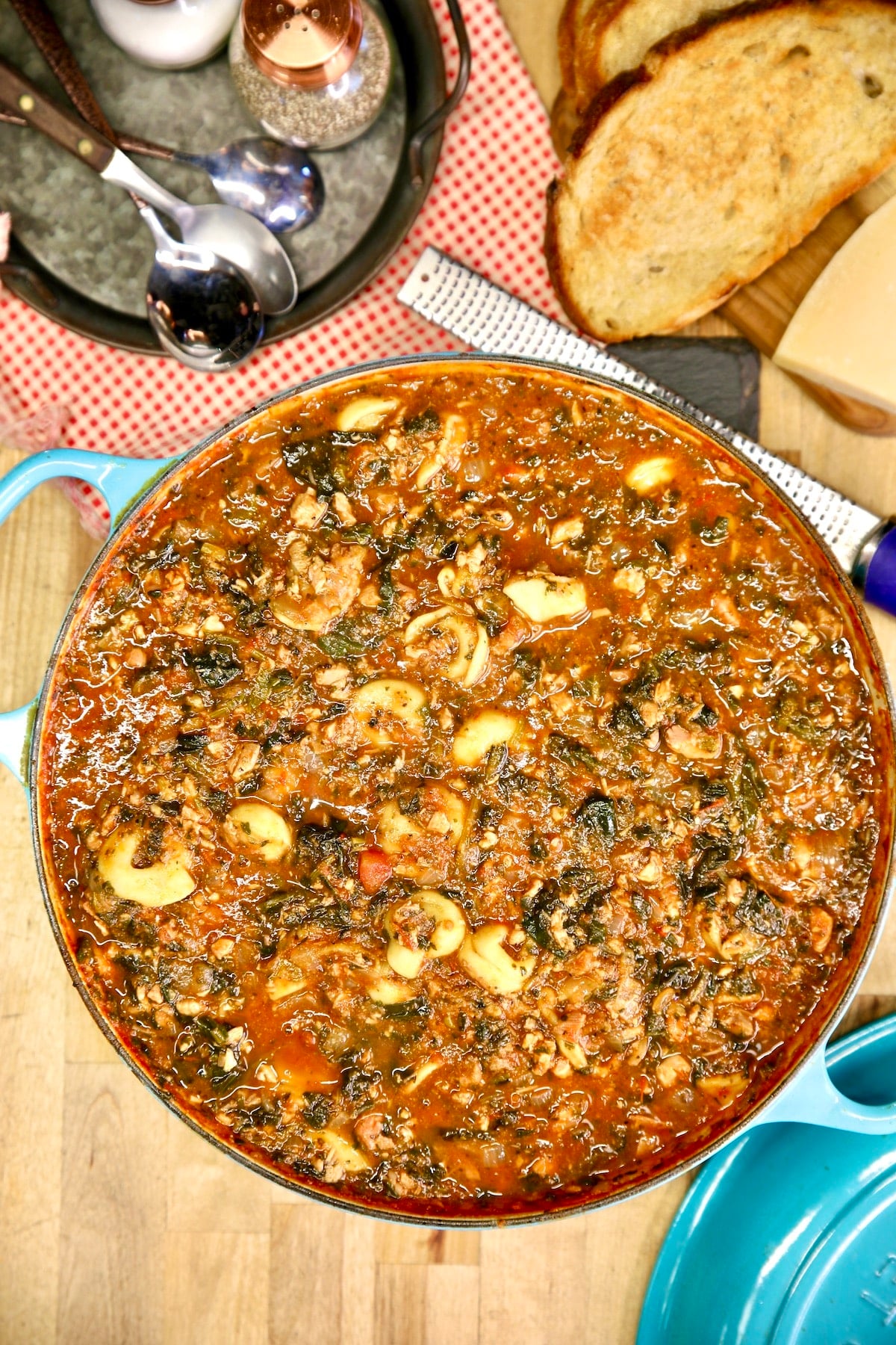 Pan of tortellini tomato soup with bread, parmesan cheese.