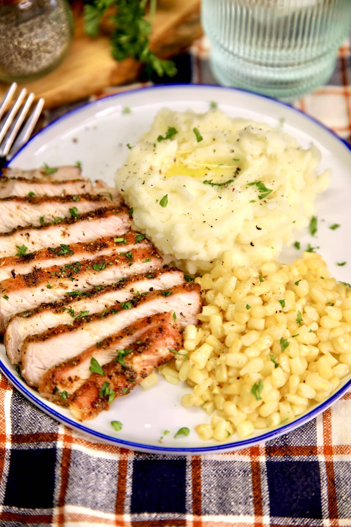 Plate with sliced pork chop, mashed potatoes, corn.