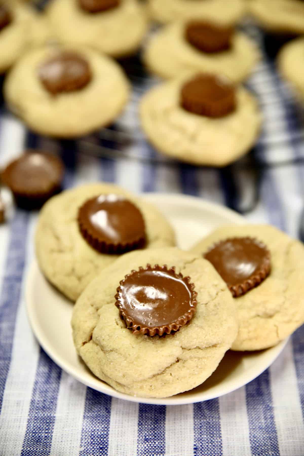 Peanut Butter Cup cookies on a plate with rack of cookies.