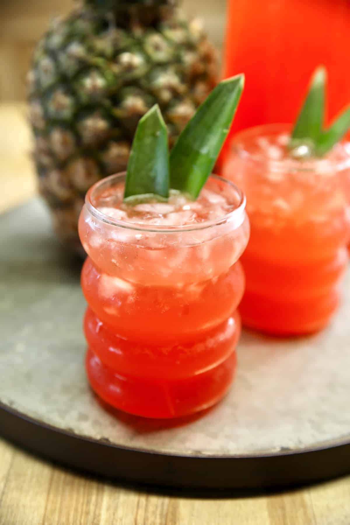 2 glasses of rum party punch, garnished with pineapple fronds.