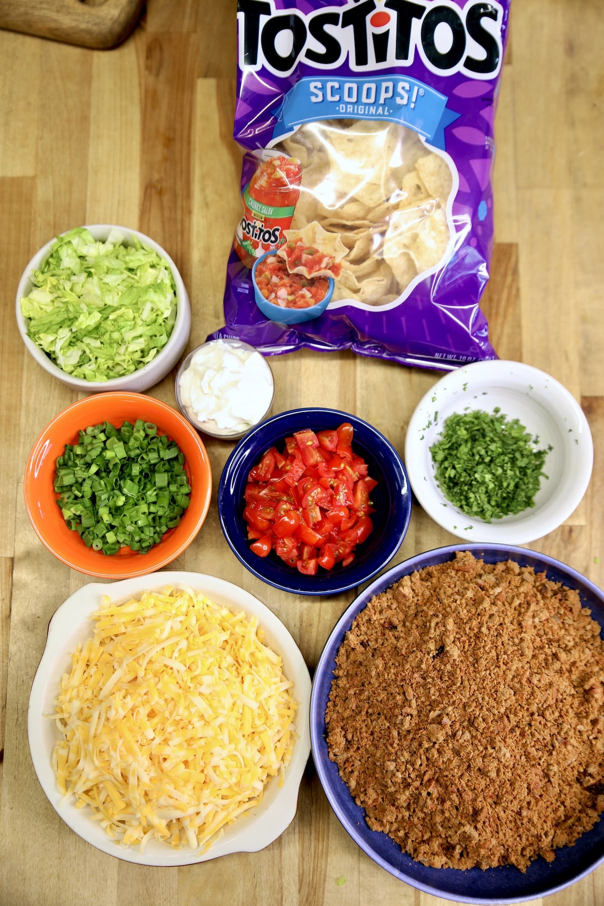 Ingredients for taco bites: taco meat, cheese, green onions, tomatoes, cilantro, lettuce, sour cream.
