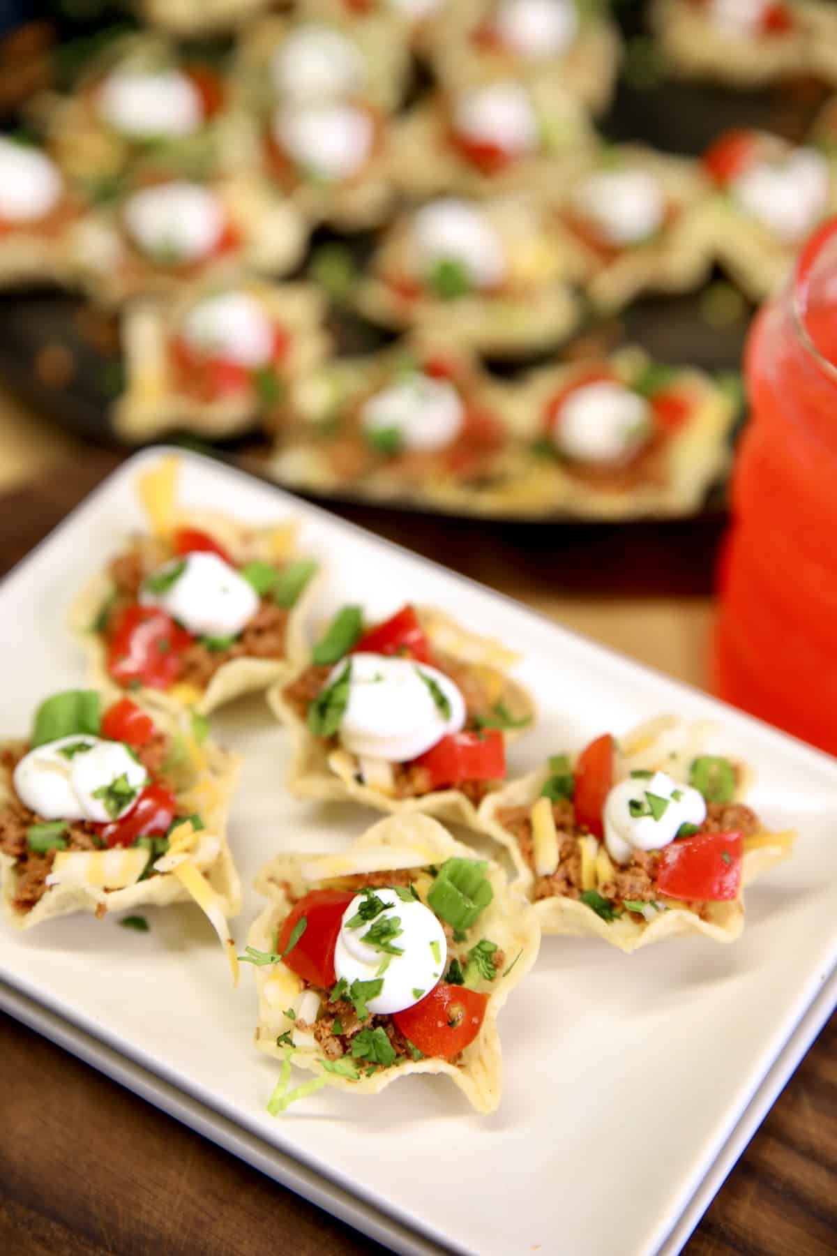 Appetizer plate with taco bites, topped with sour cream and tomatoes.