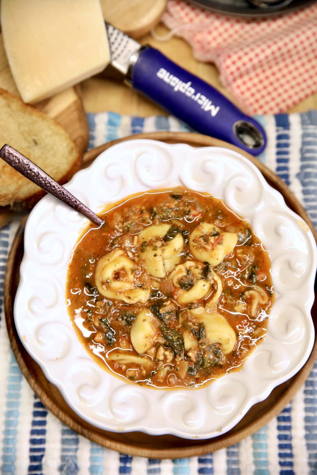 Bowl of tortellini soup with tomato, spinach and chicken.