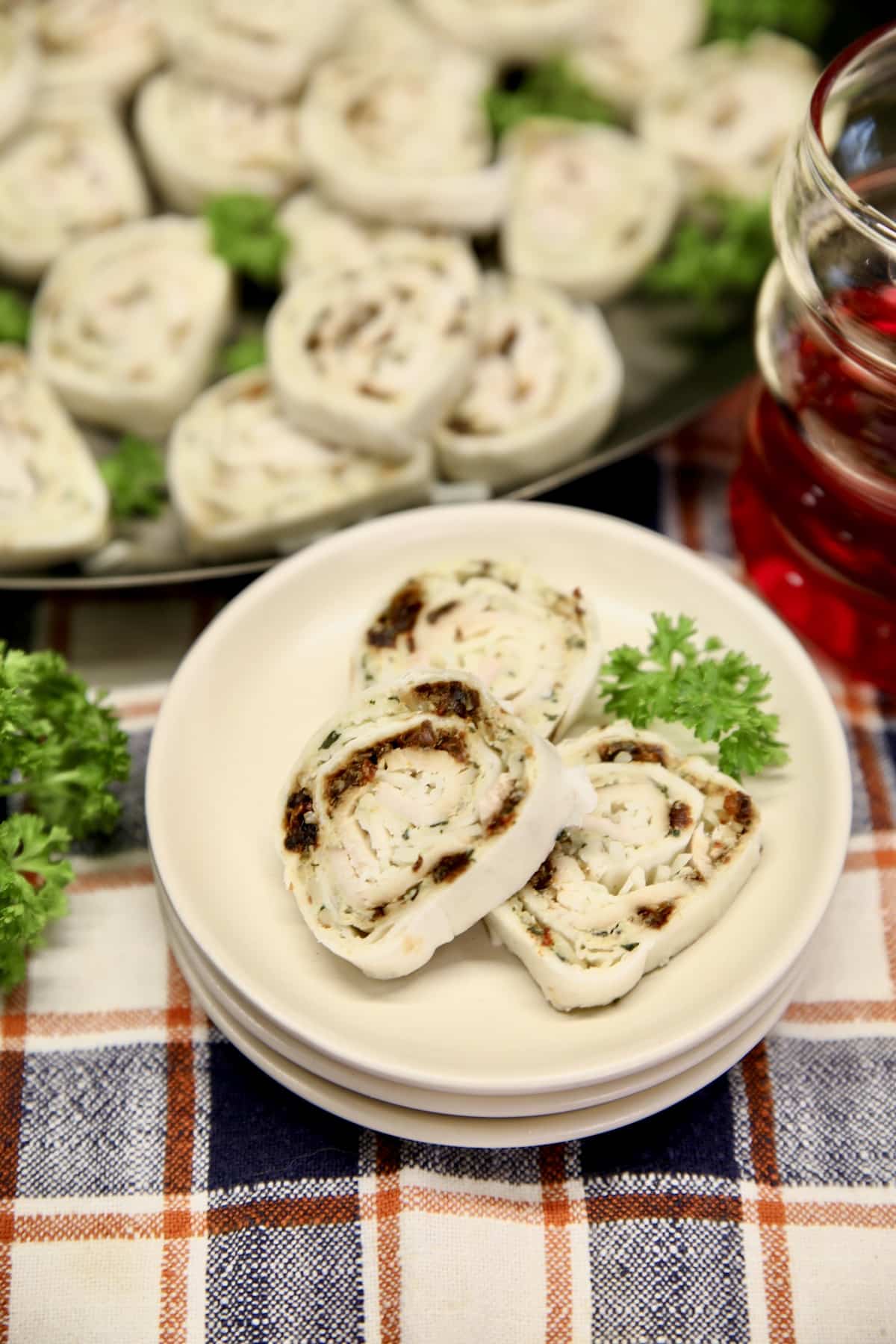 3 turkey pinwheels on a small plate, platter in background.