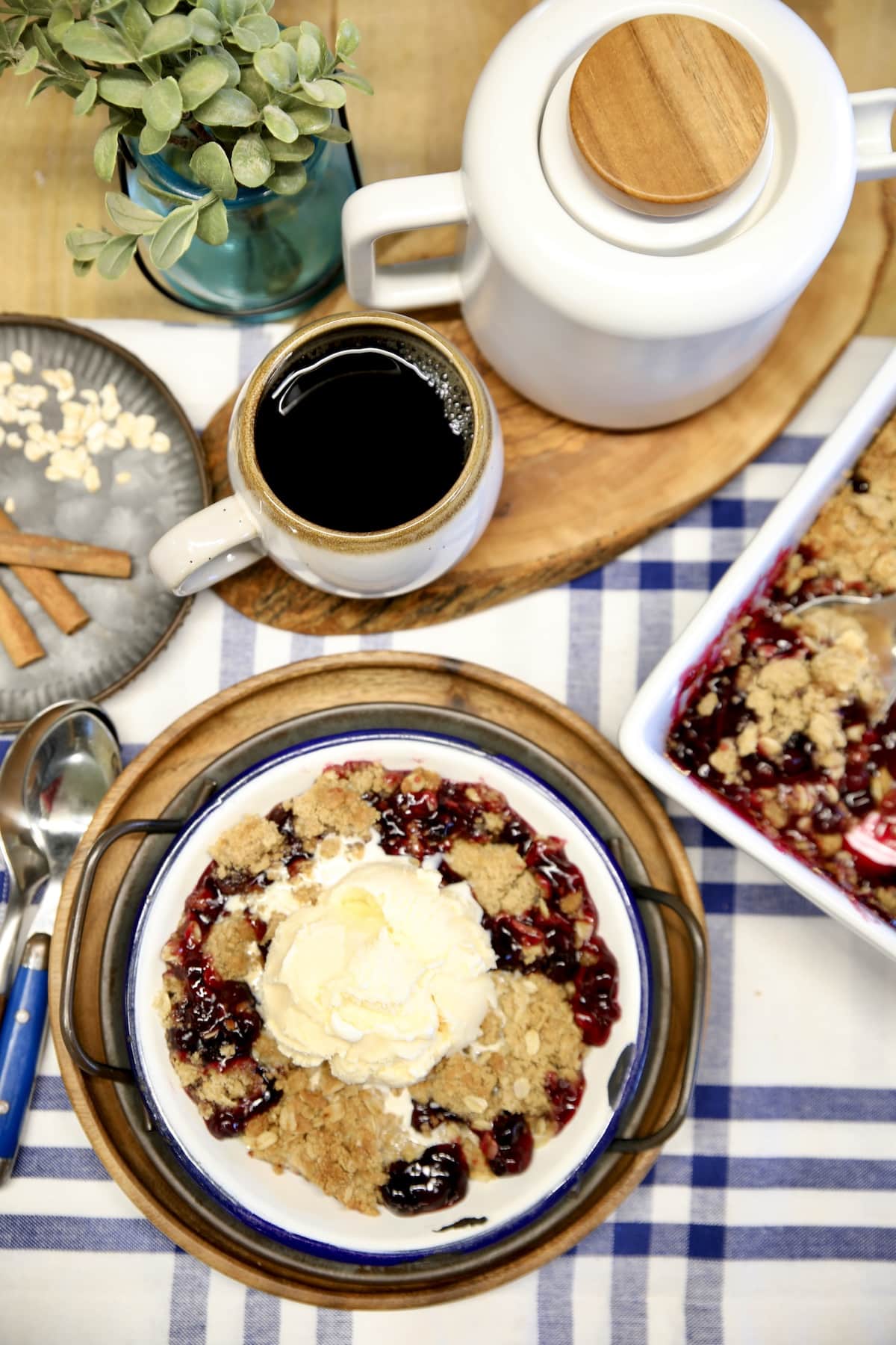 Blueberry Crisp with vanilla ice cream on a plate, cup of coffee, coffee pot.