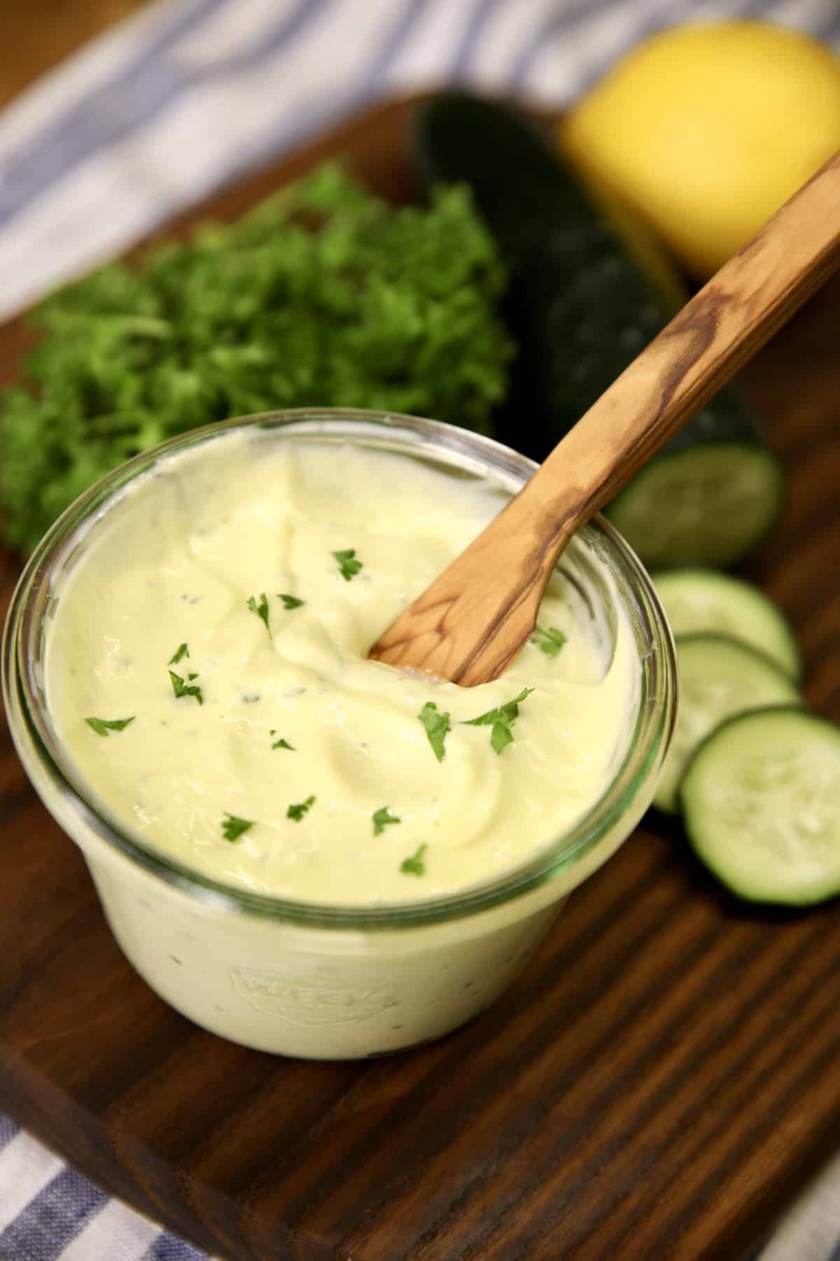 Jar of homemade mayo with cucumber in a jar with wood knife.
