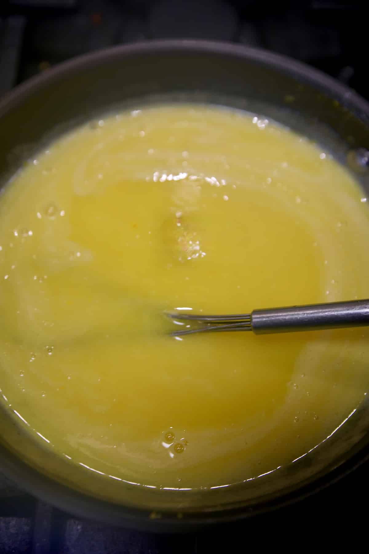 Cooking lemon curd with whisk.