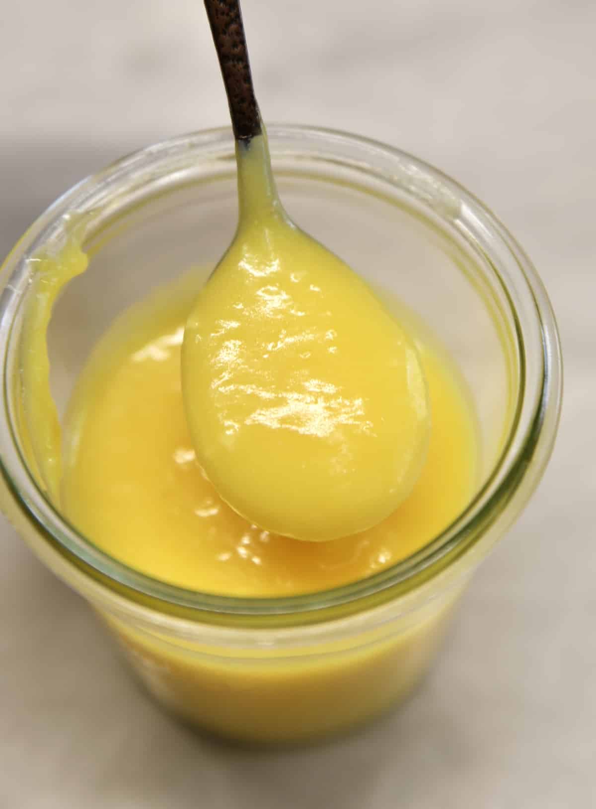 Jar of lemon curd with spoonful. 
