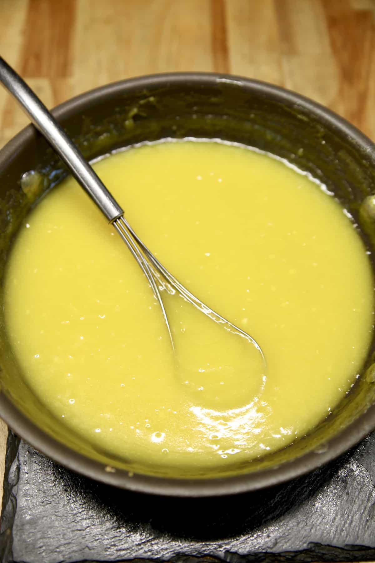 Lemon curd in a pan with whisk.