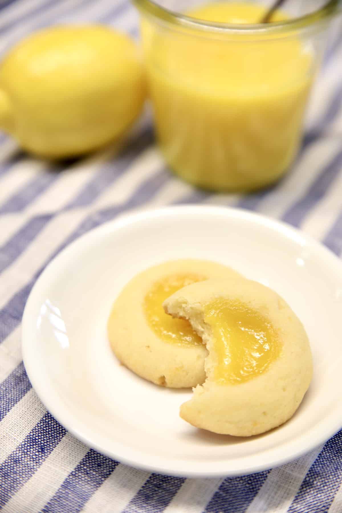 2 lemon curd cookies on a small plate, one with bite out of it.