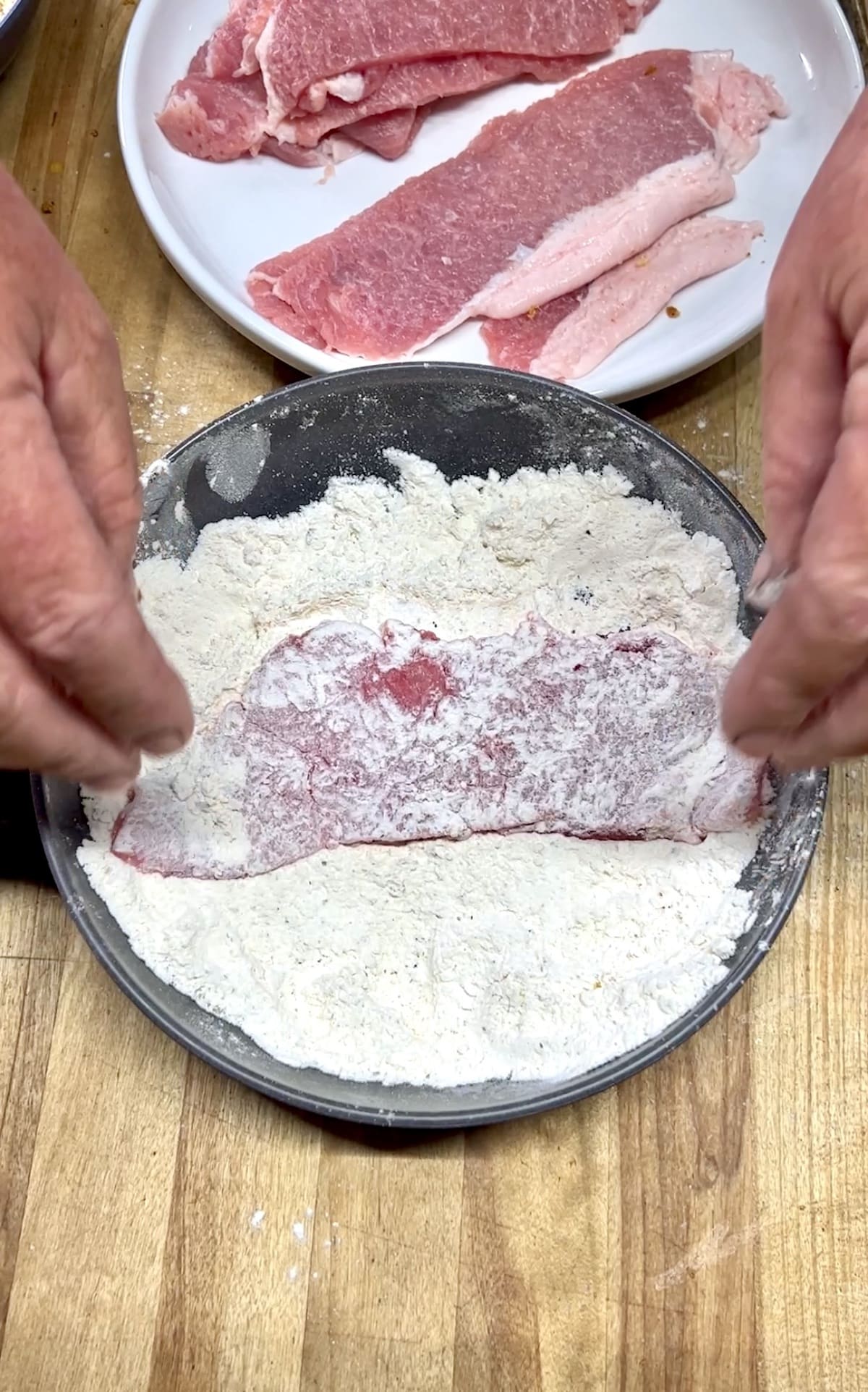 Dredging pork cutlets in flour. 