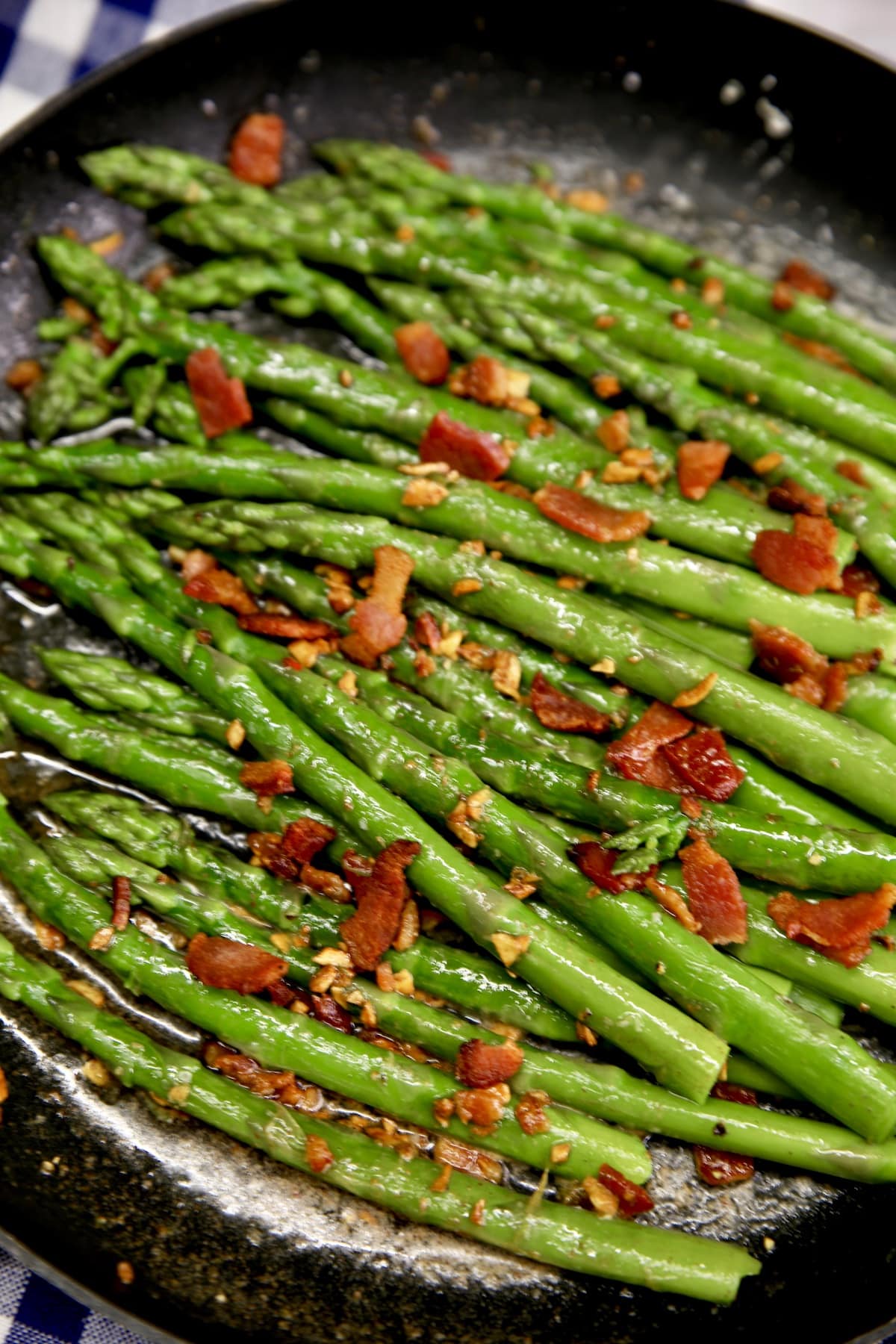 Closeup of asparagus in a pan with bacon crumbles.