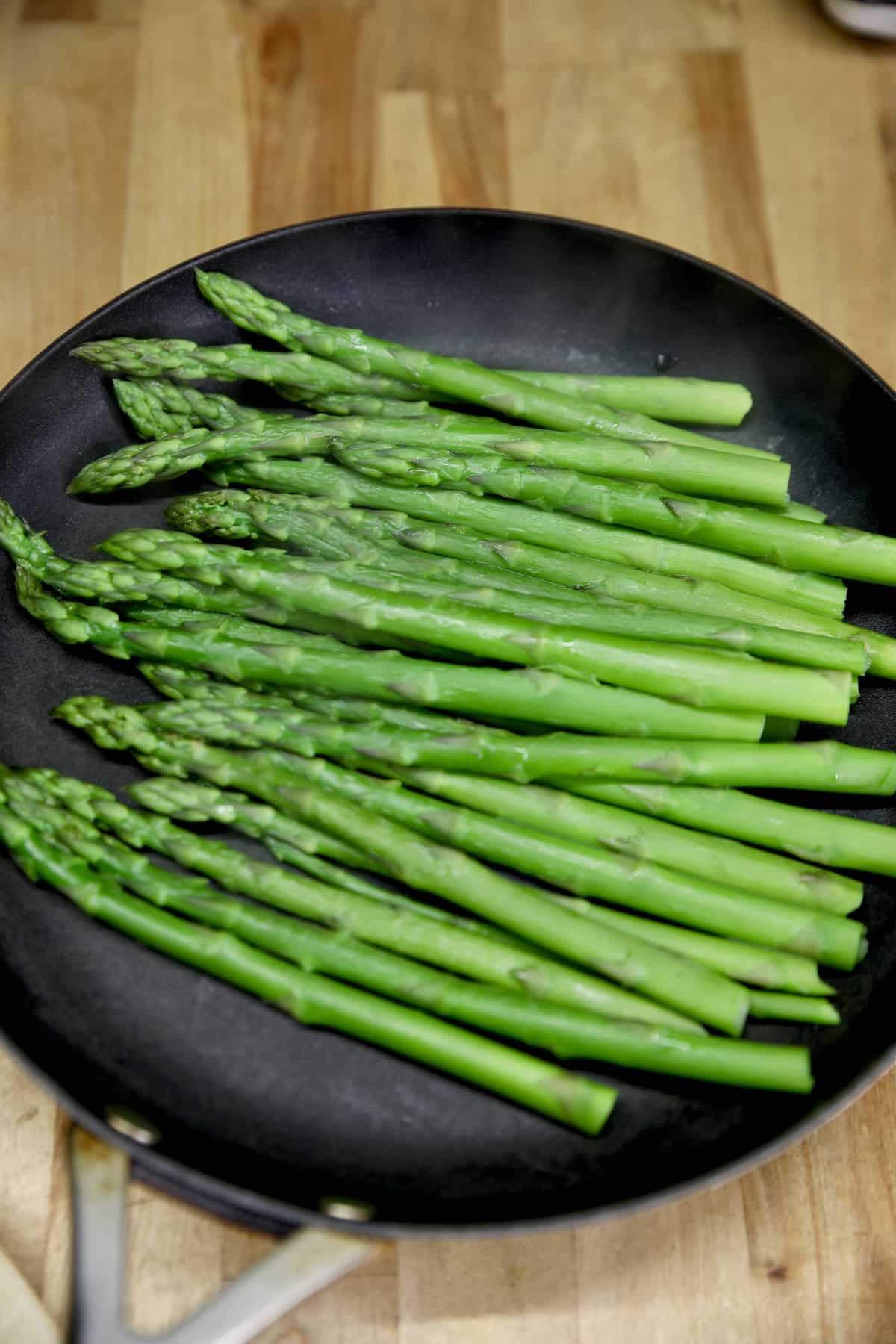 Parboiled asparagus in a pan, water drained.