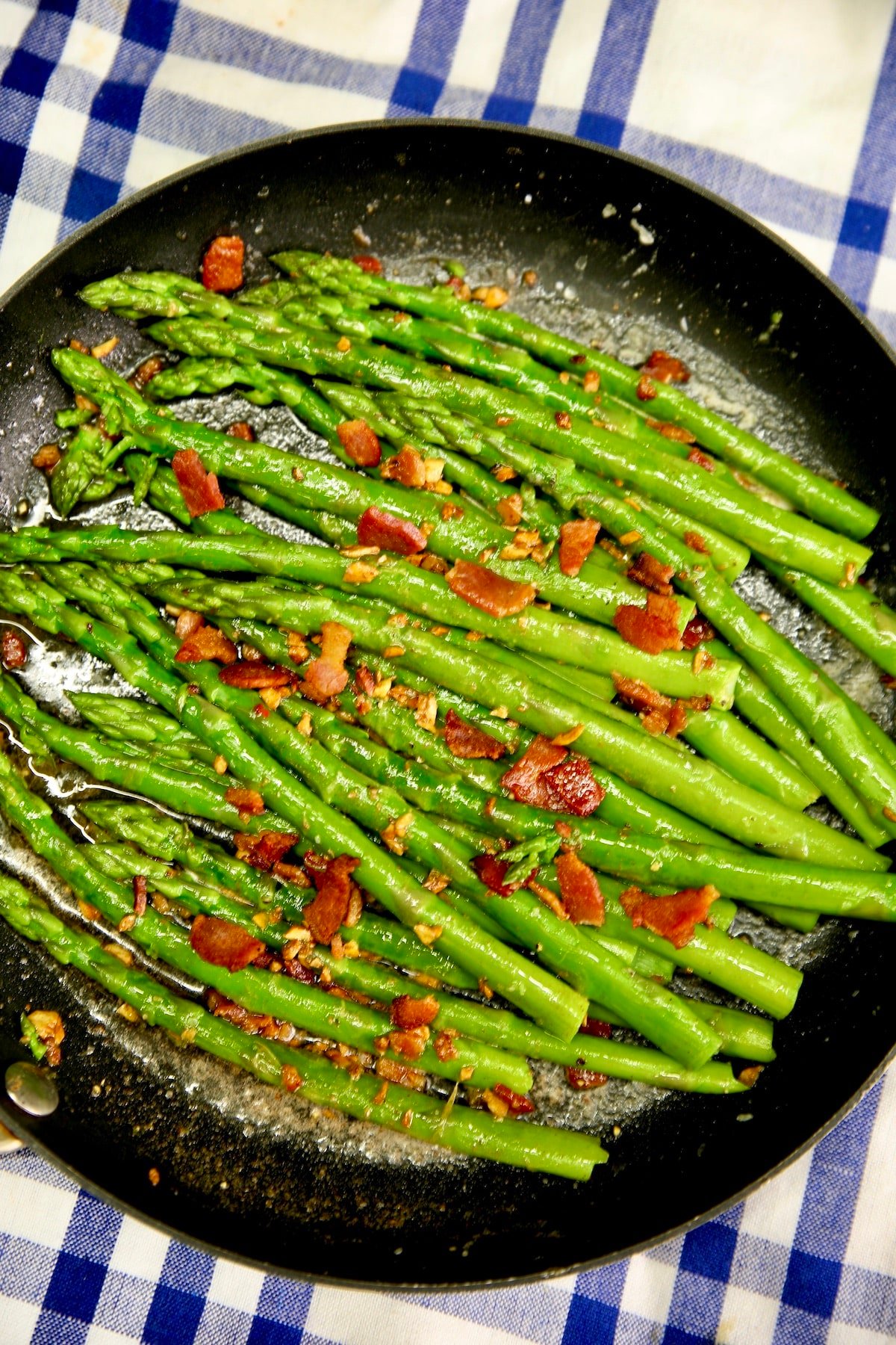 Skillet with cooked asparagus spears and crisp bacon.