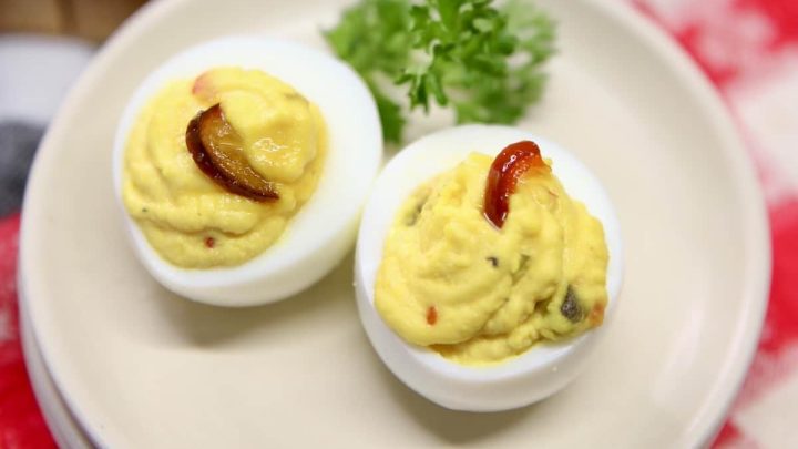 2 deviled eggs on a small plate with parsley.