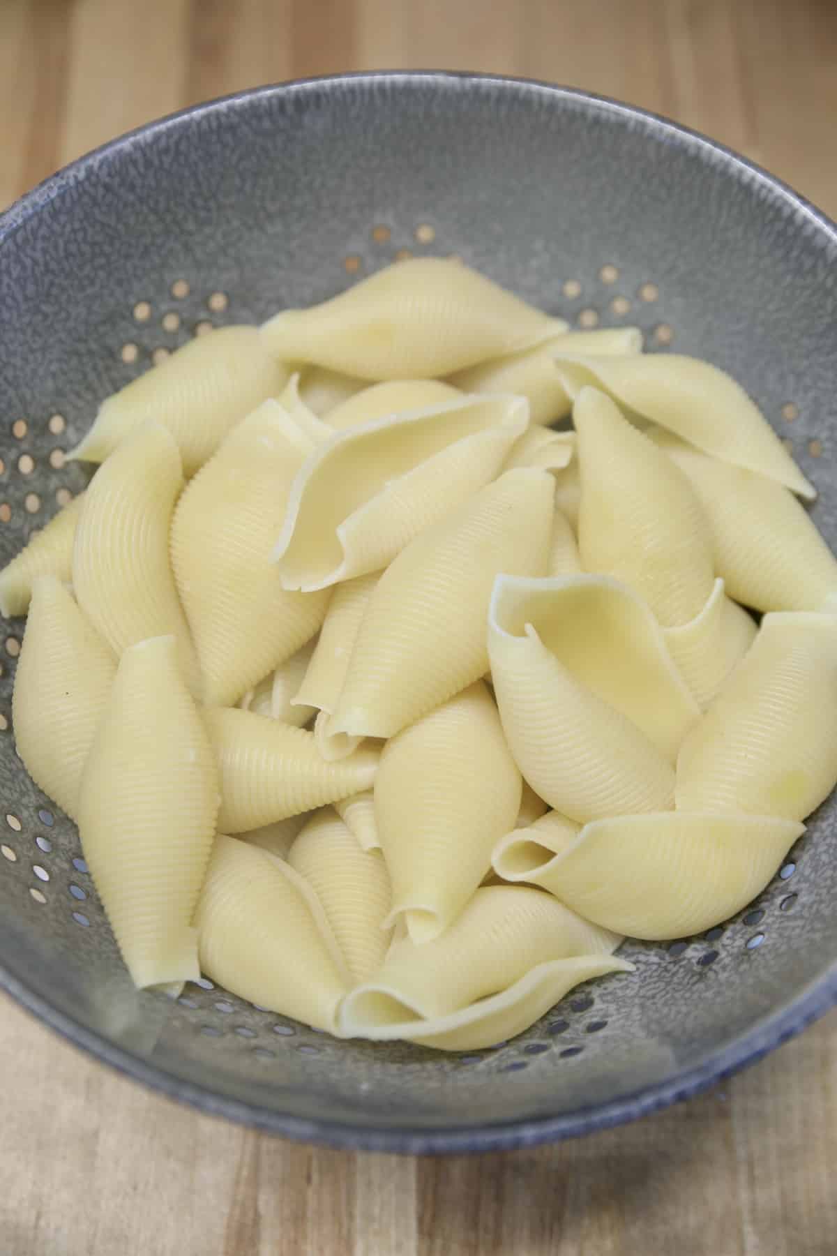 Cooked and drained jumbo pasta shells in a colander.