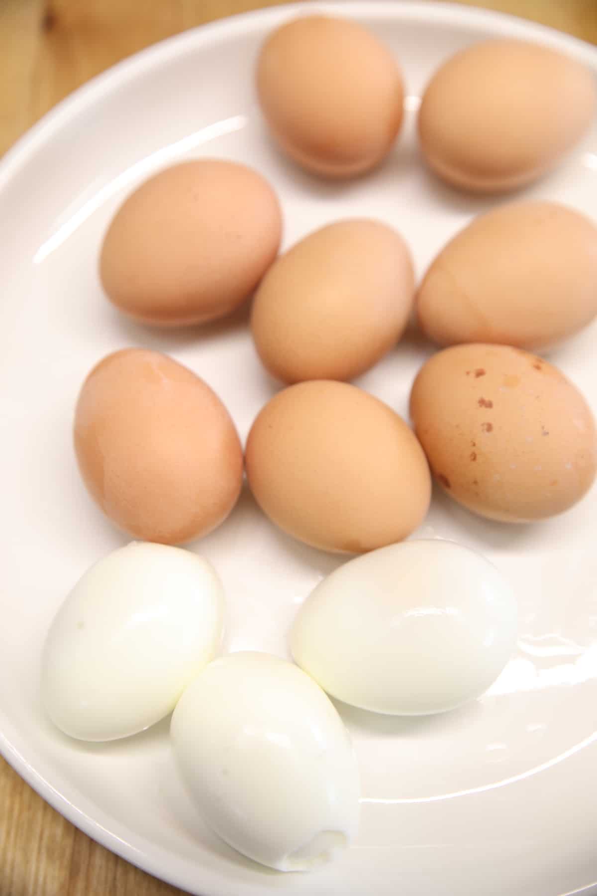 Plate of hard boiled eggs, 3 peeled. 