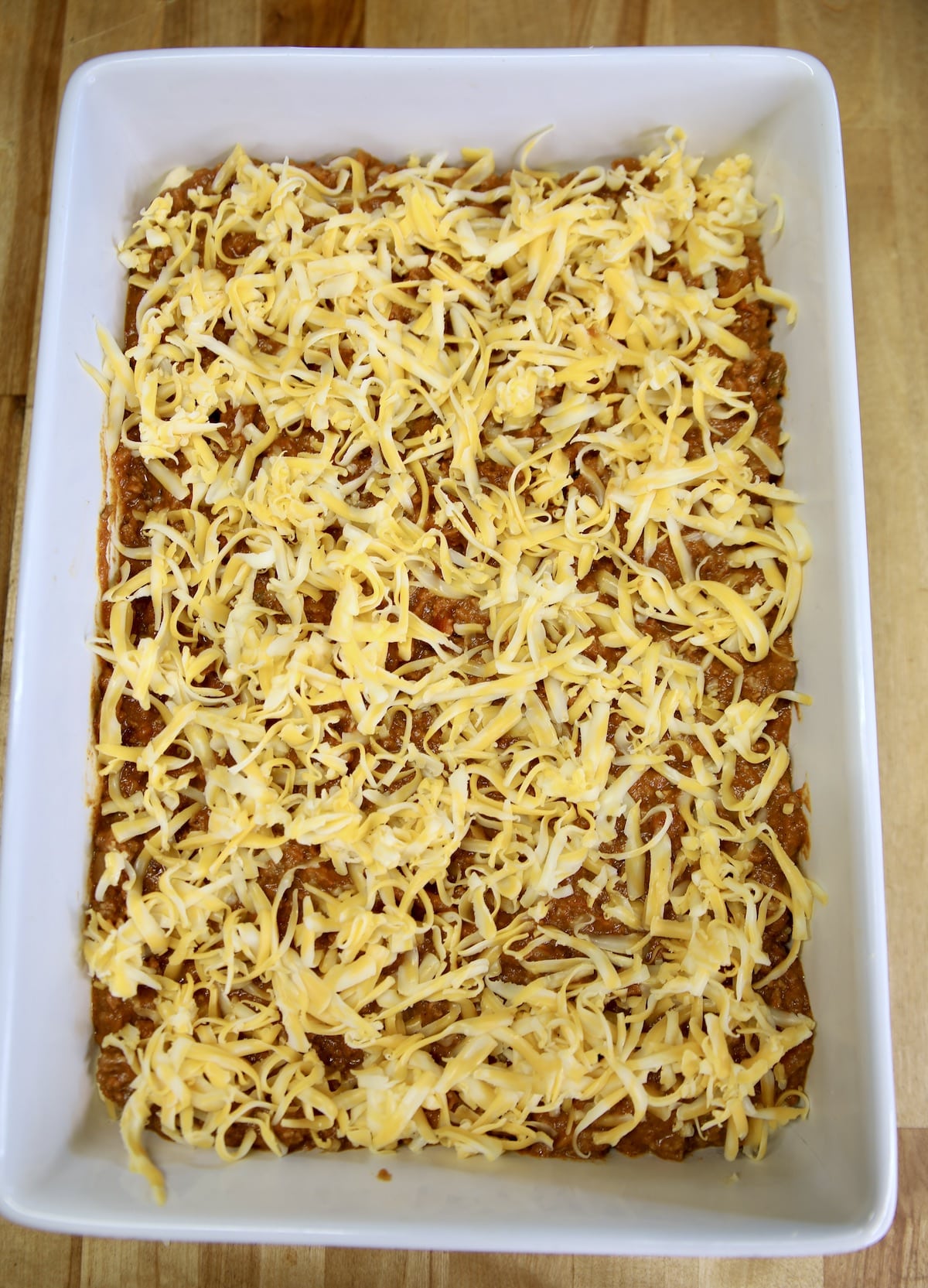 Ground beef and bean burrito casserole with shredded cheese -unbaked.