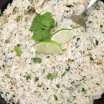 Closeup of bowl of cilantro lime rice, lime slices cilantro garnish.