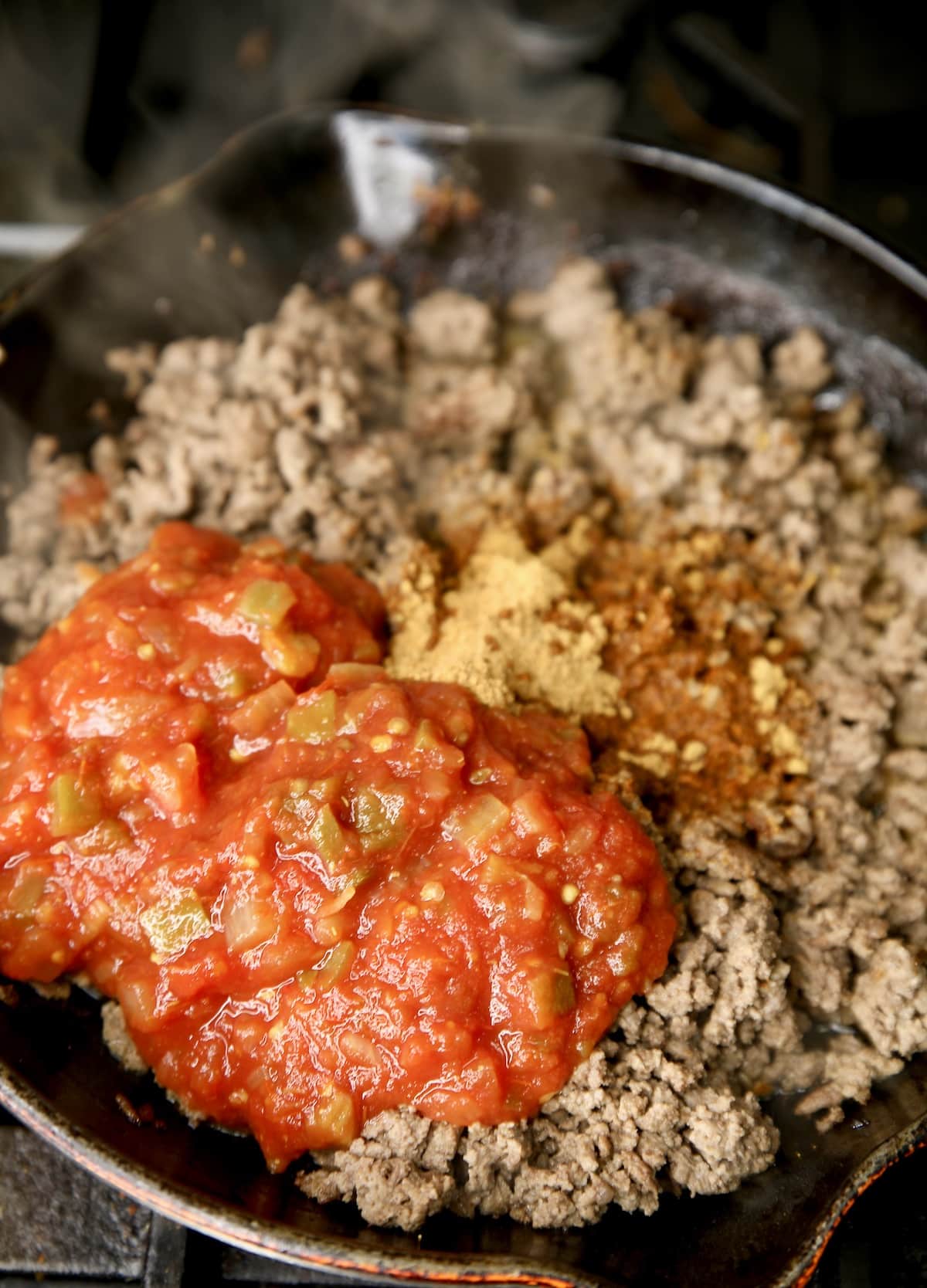Ground beef in a skillet with taco seasoning and salsa.