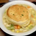 Chicken pot pie casserole with a biscuit on top in a bowl.