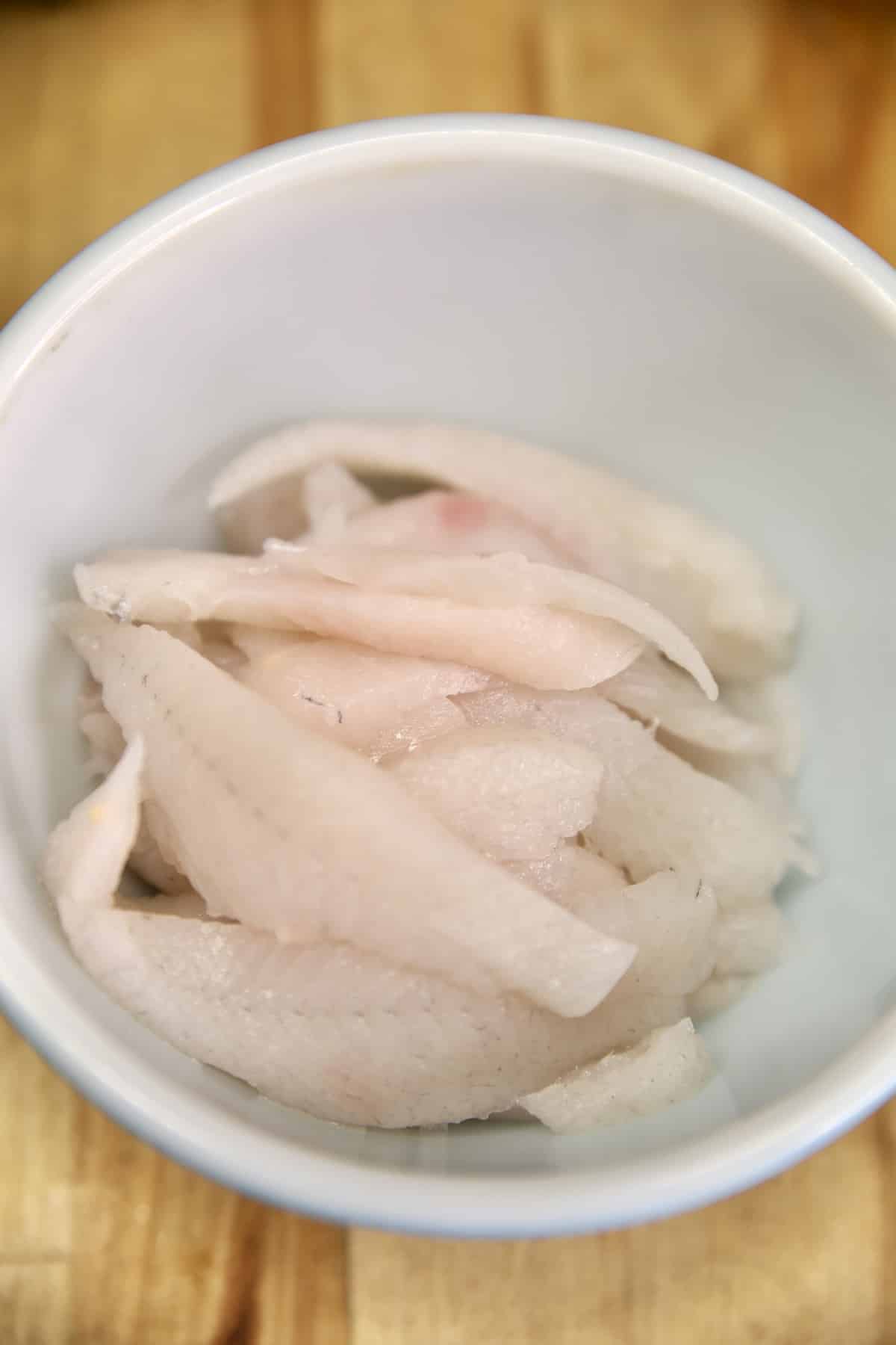 White fish filets in a bowl.