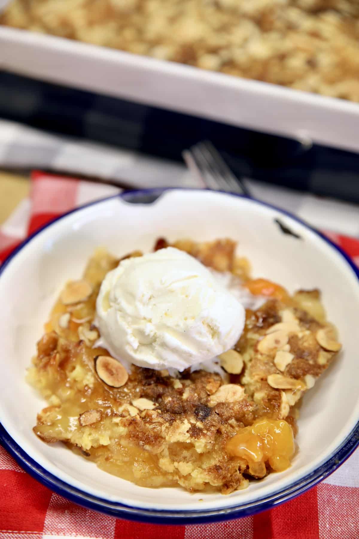 Apricot dump cake with ice cream on a plate.