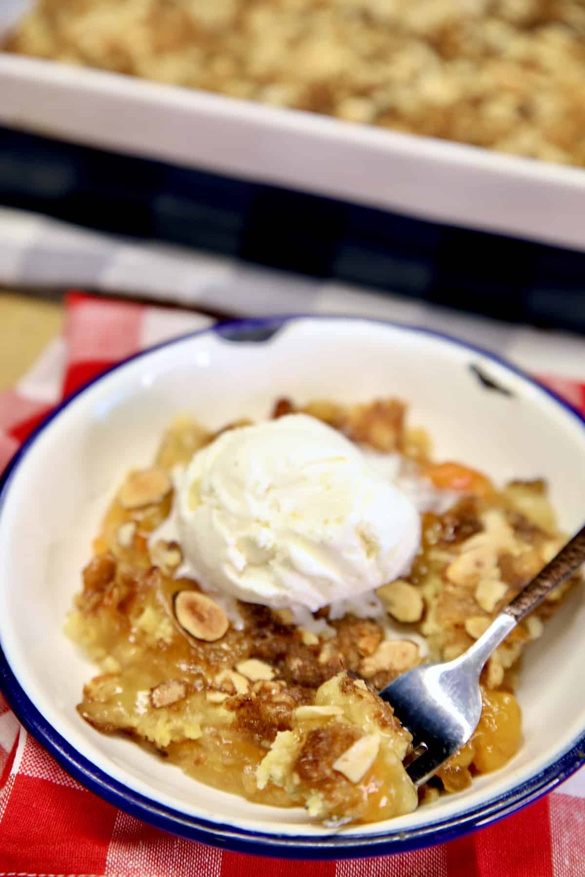 Apricot Dump Cake with vanilla ice cream on a plate with a fork.