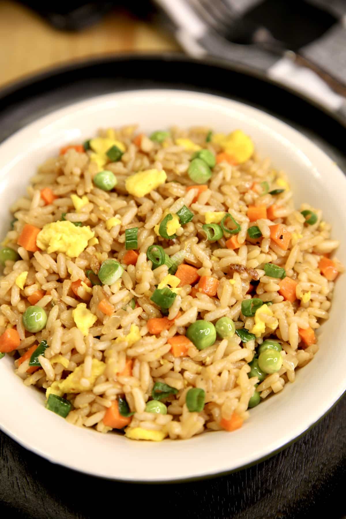 Egg fried rice in a bowl on a black platter.