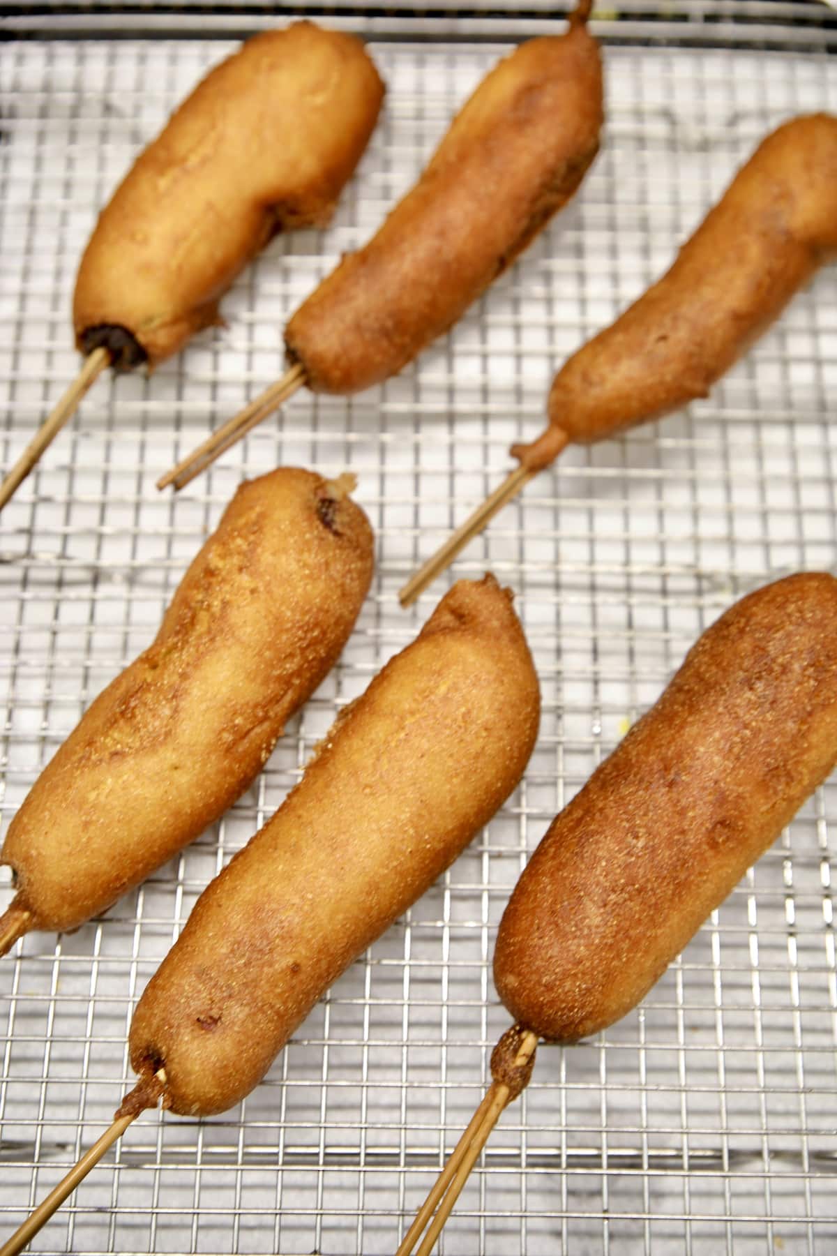 6 Corn dogs on a wire rack. 