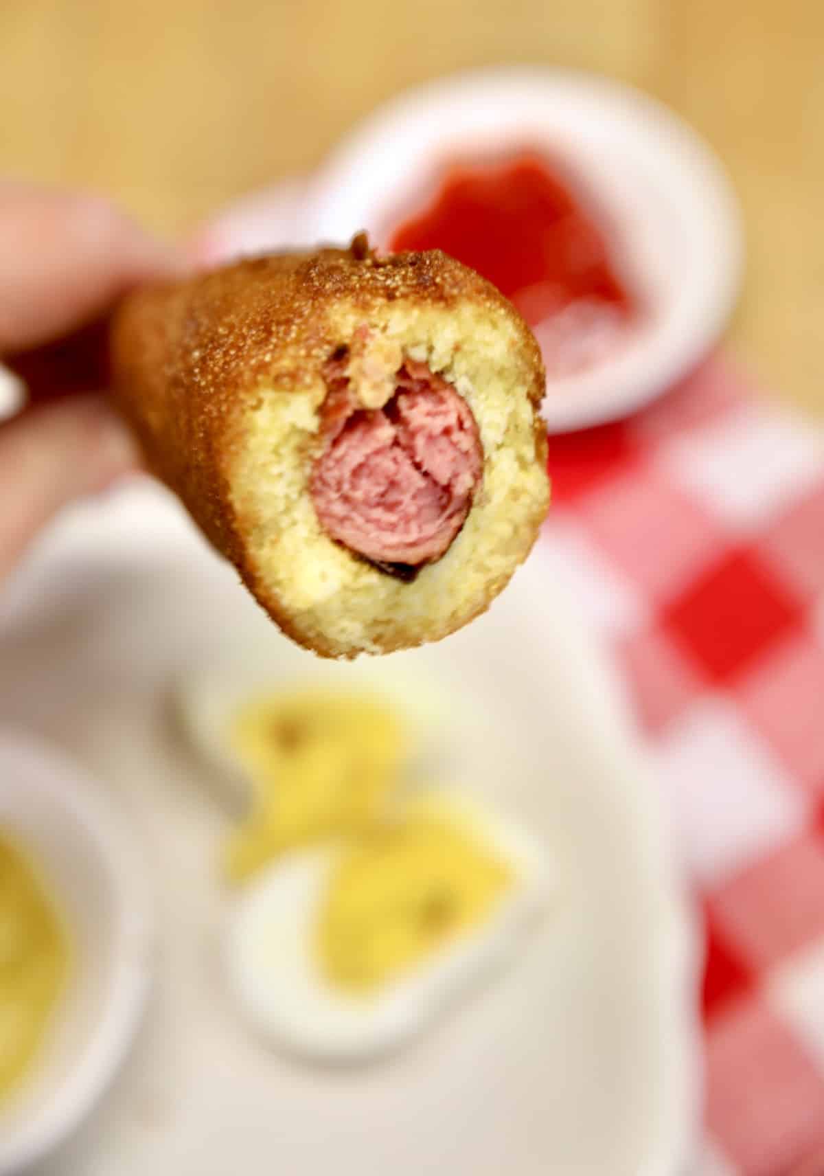Closeup of a corn dog on a stick with hot dog showing.