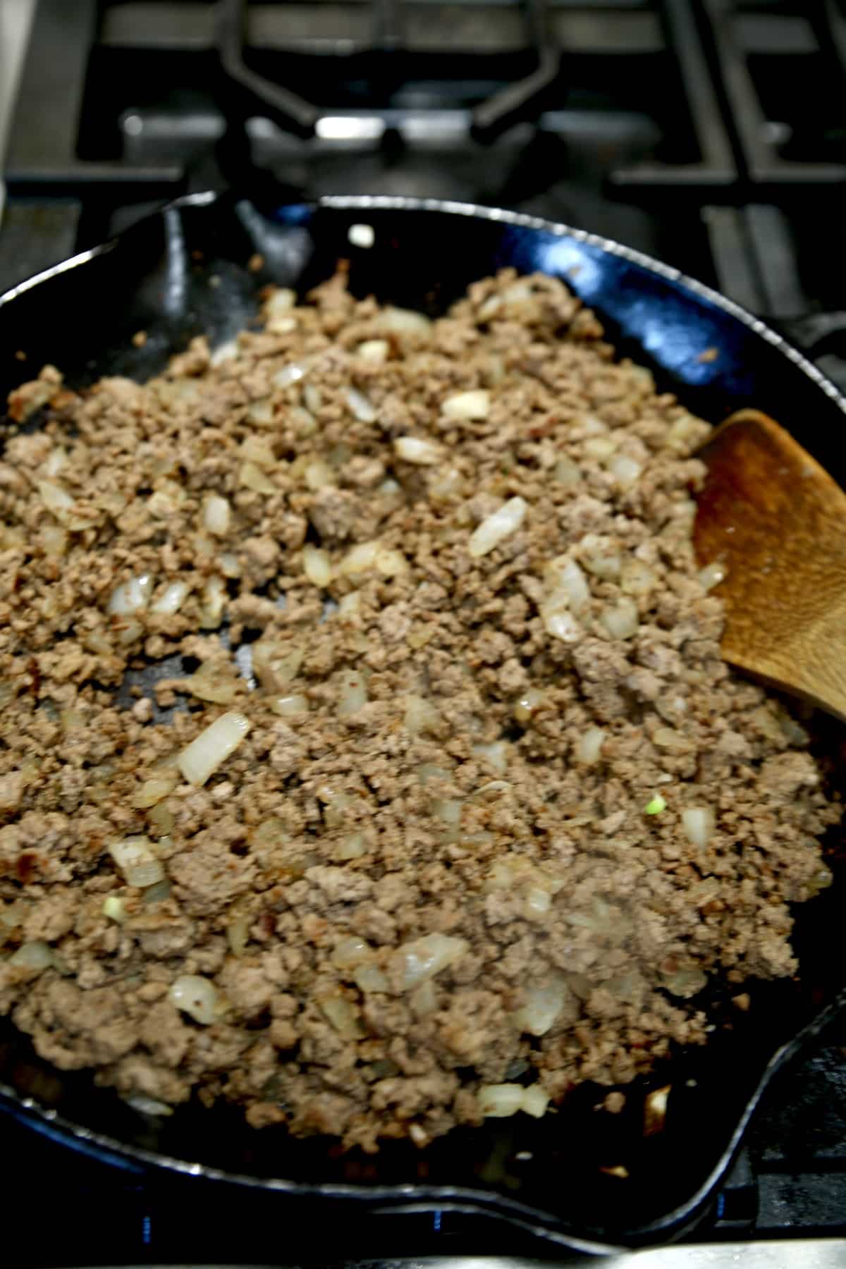 Browned ground beef and diced onion in a skillet.