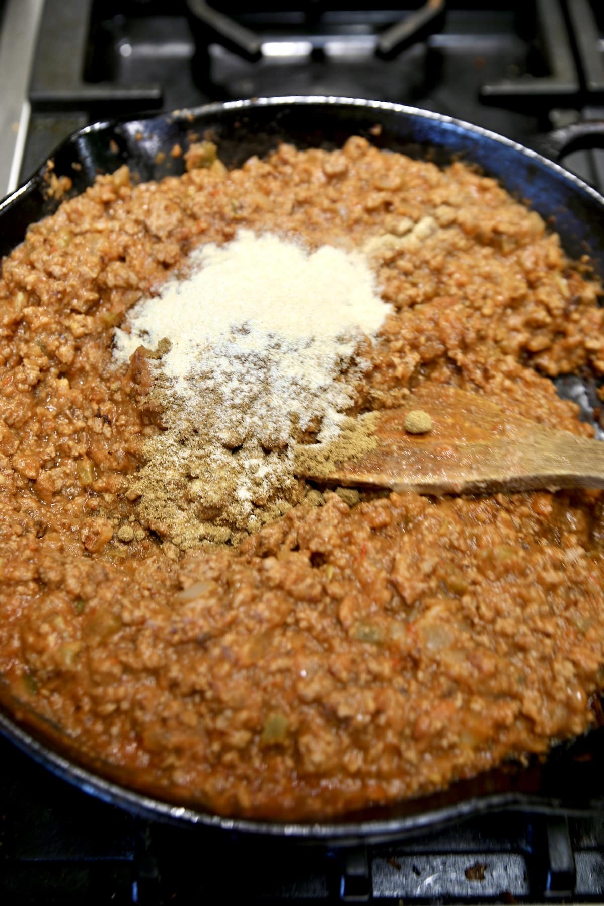 Adding seasonings to burrito filling in a skillet.