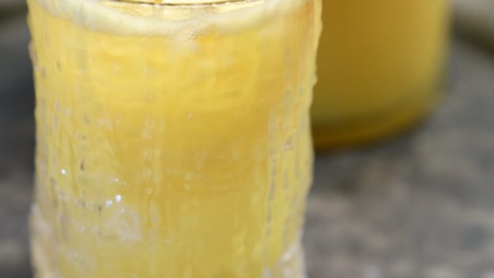 Peach mango wine punch in a glass with peach slice.