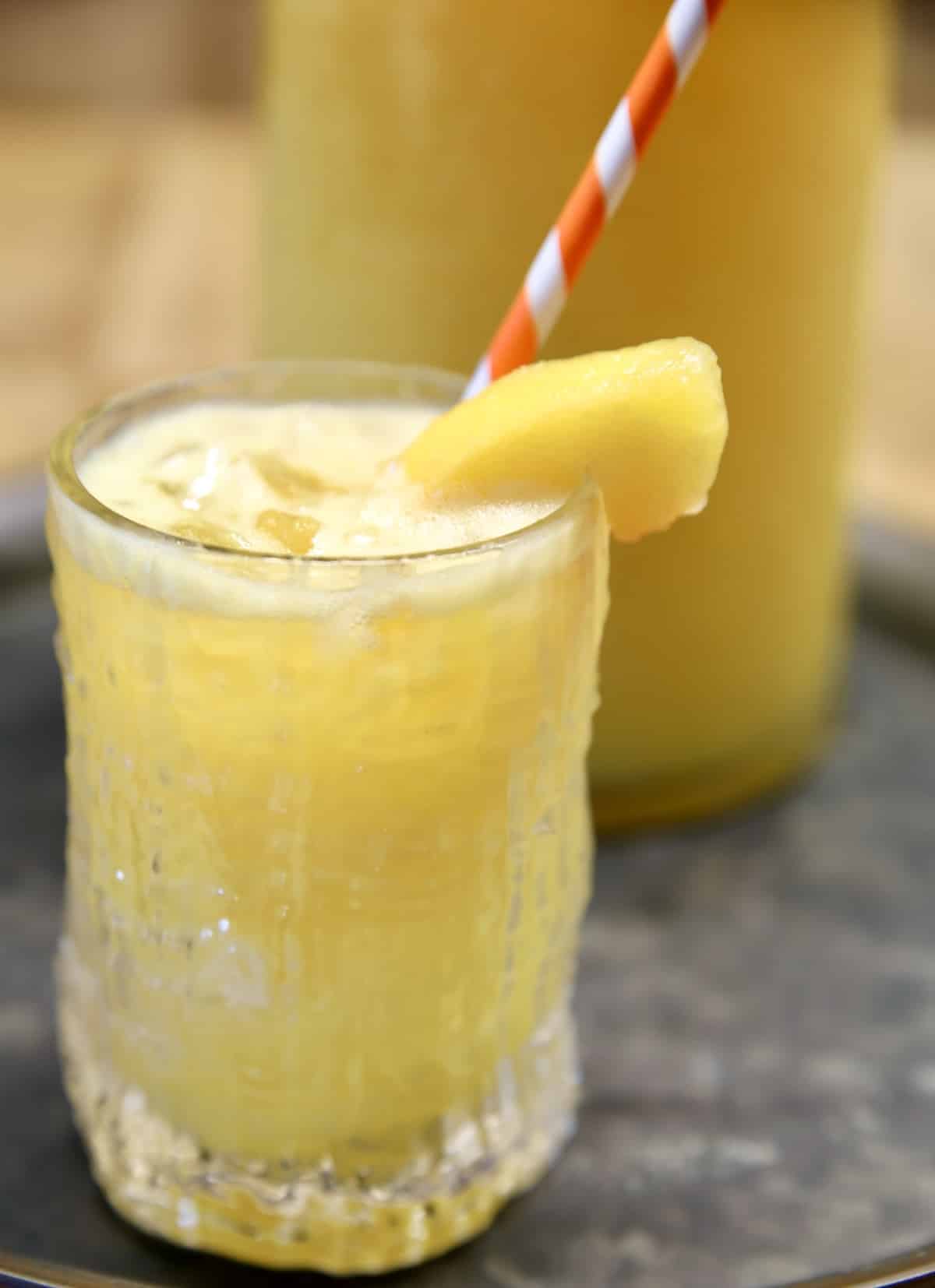 Peach Mango Moscato Punch in a glass with orange stripe straw.