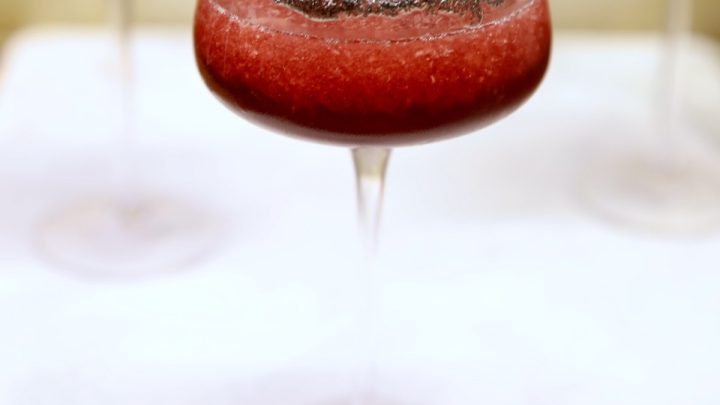 Black cherry margarita in a coupe glass with black lava salt rim.